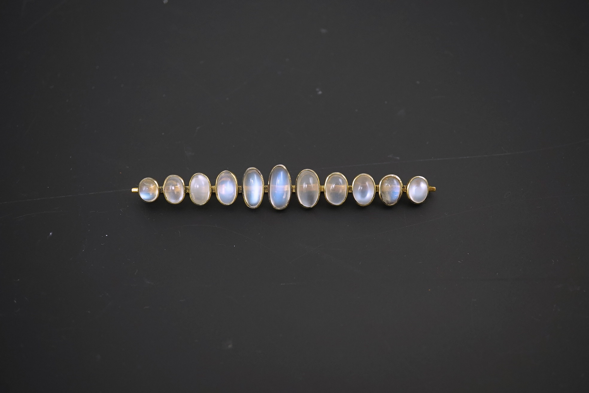 A gold and eleven stone graduated cabochon moonstone set bar brooch